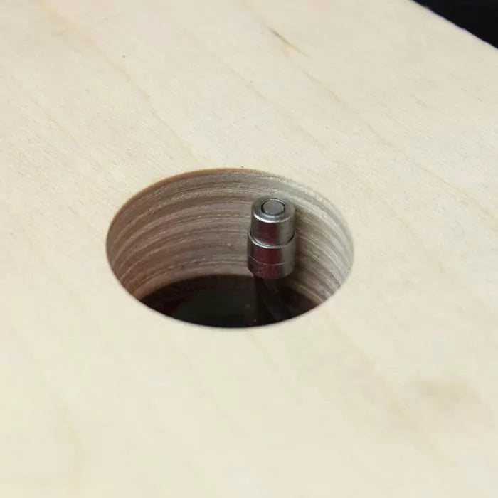 Close-up of a woodworking router bit cutting a clean hole in plywood