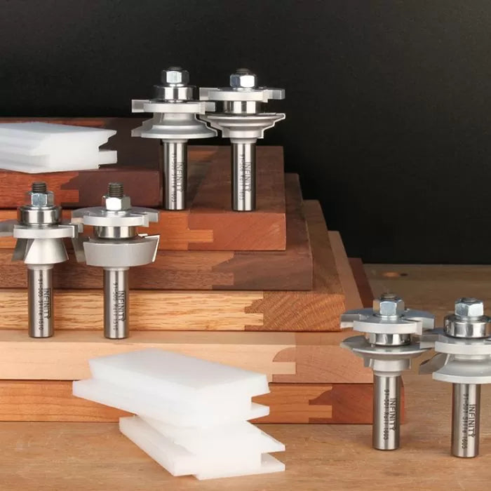 Carbide joinery router bits set displayed on stacked hardwood boards with sample joints.