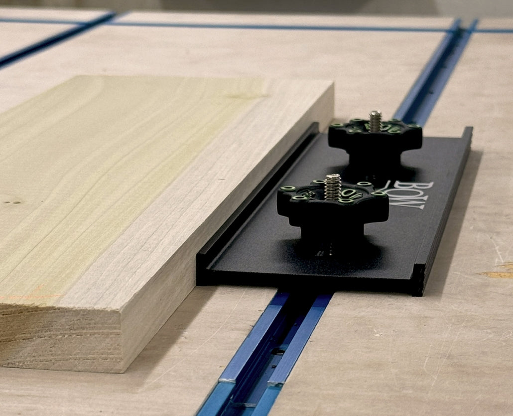 Bow clamp securing wood board on woodworking table with T-track system