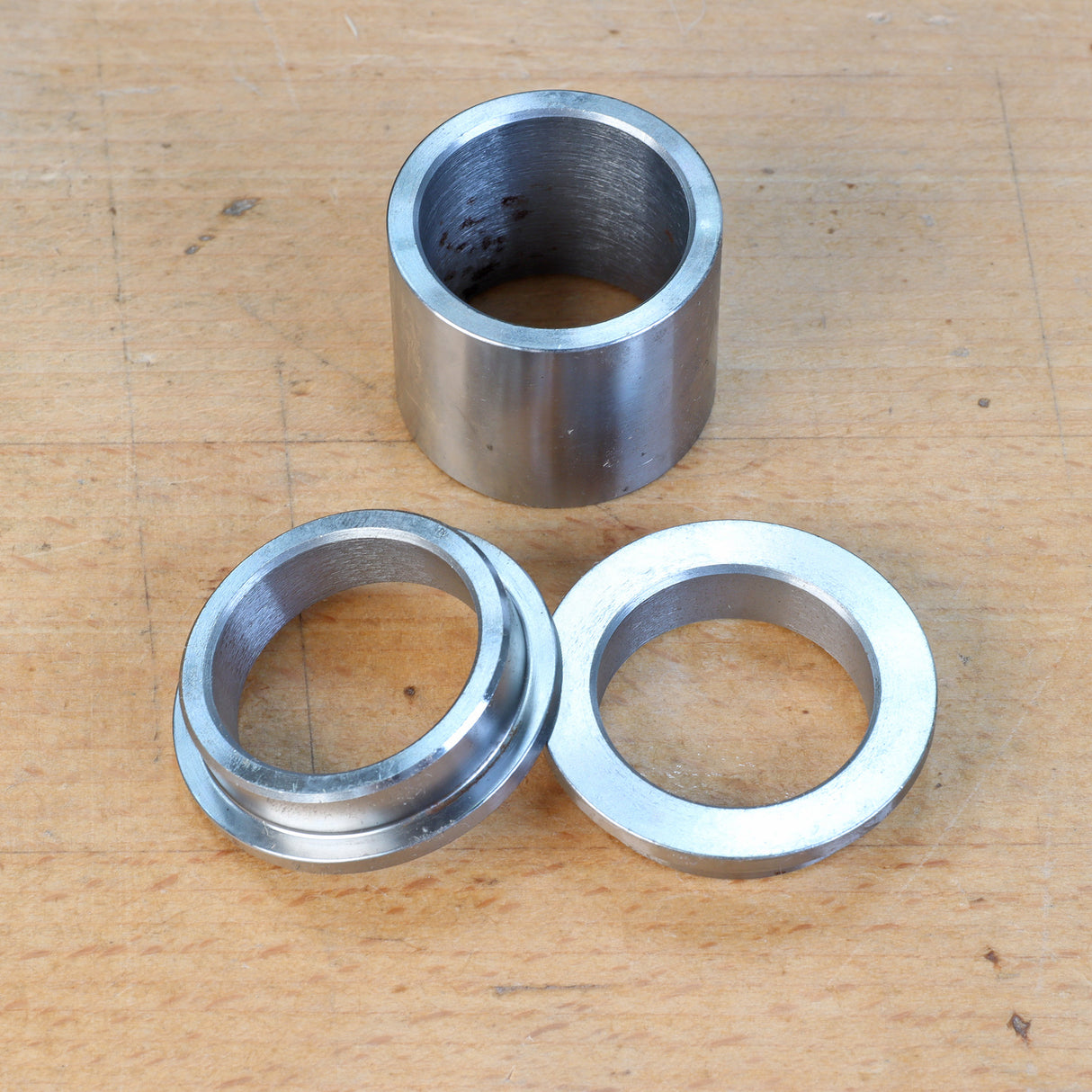 Steel router table insert rings and bushing set on a wooden surface for woodworking