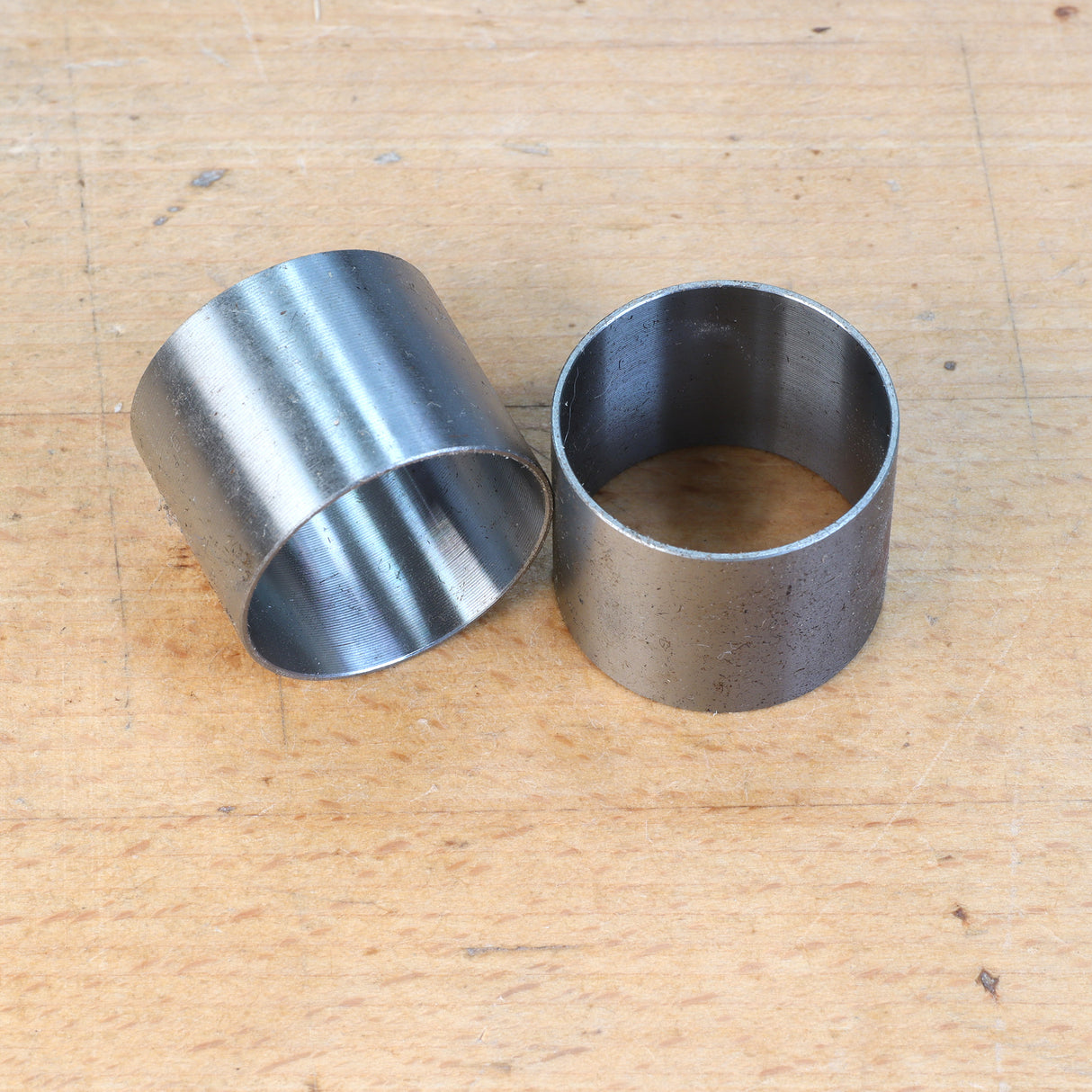 Pair of metal bushings for woodworking tools on a wooden surface