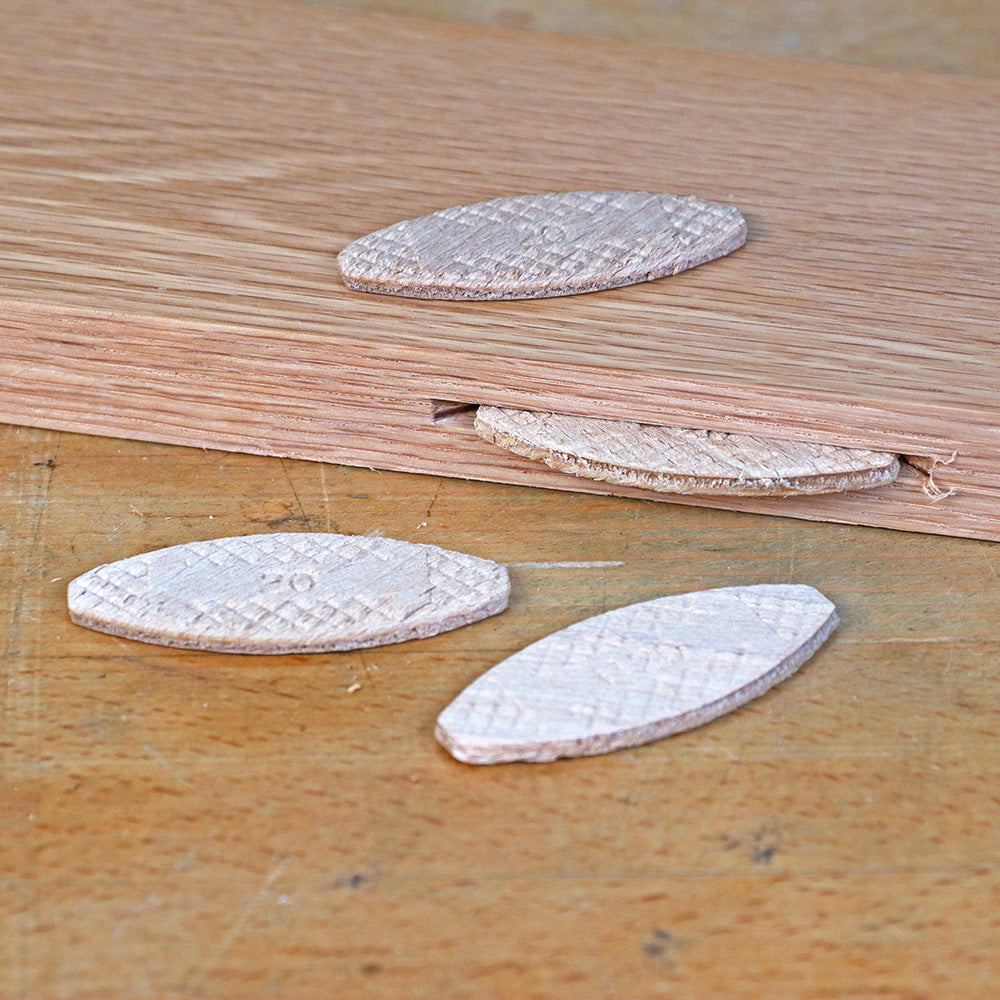 Wood biscuits and biscuit slot in wood plank on workbench for woodworking joinery