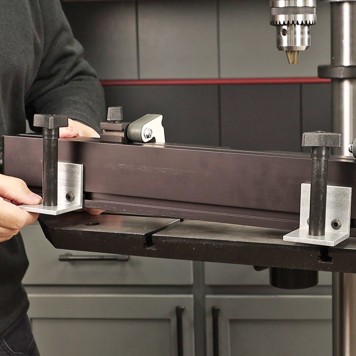 Drill press fence system mounted on a drill press table in a woodworking shop