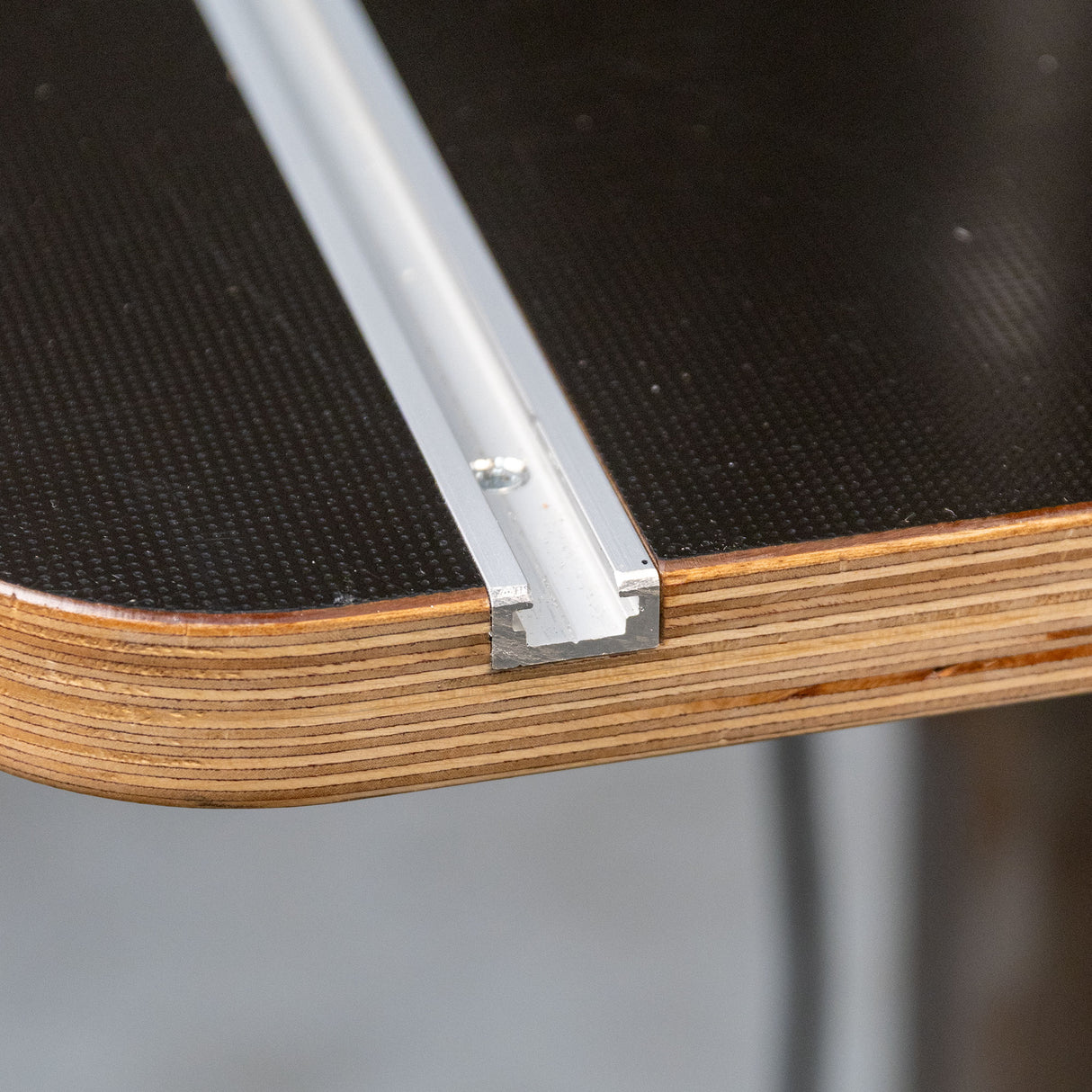 Close-up of drill press table corner with T-track aluminum combo rail installed