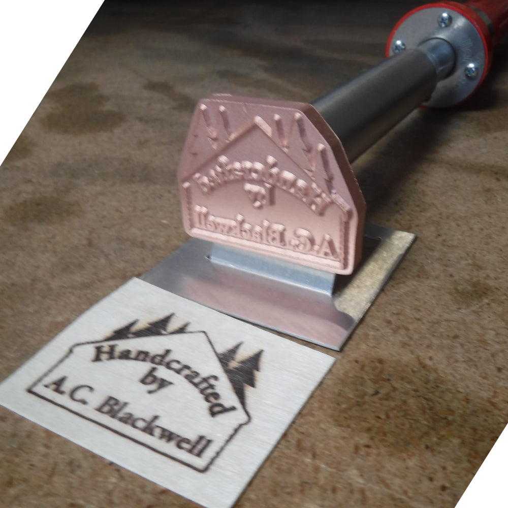 Custom metal branding iron for woodworking with stamped wooden label on workbench