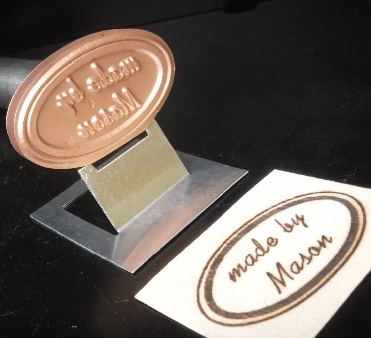 Custom oval branding iron for woodworking with 'made by Mason' woodburned stamp.