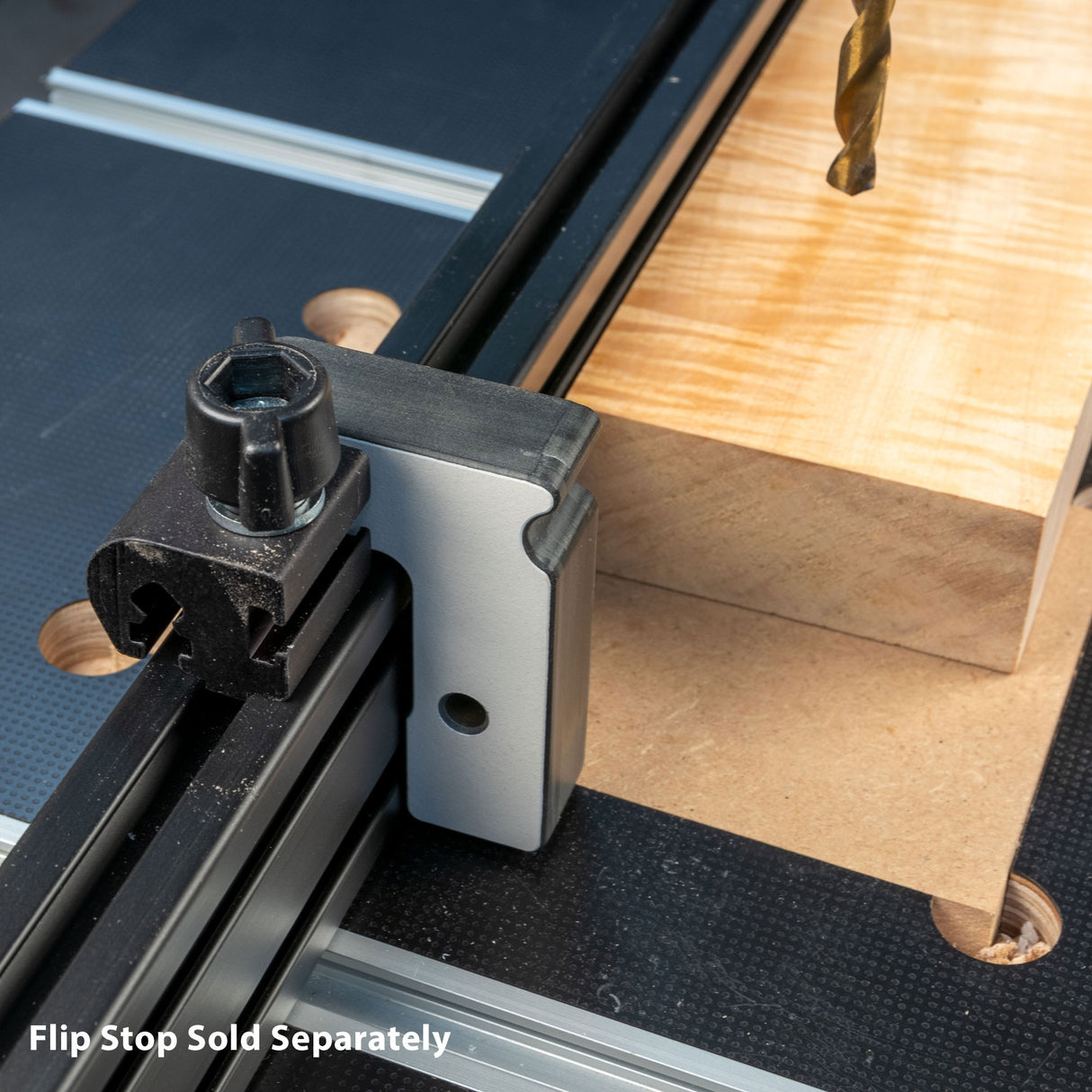 Drill press fence with flip stop attached, guiding a wood block on a workbench