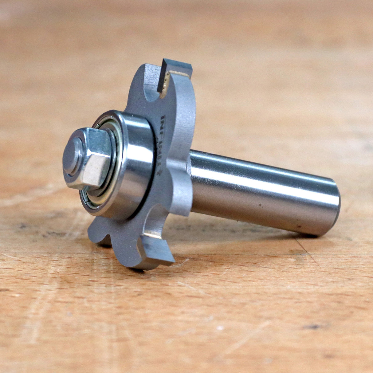 Close-up of a woodworking router bit with bearing on a wood surface