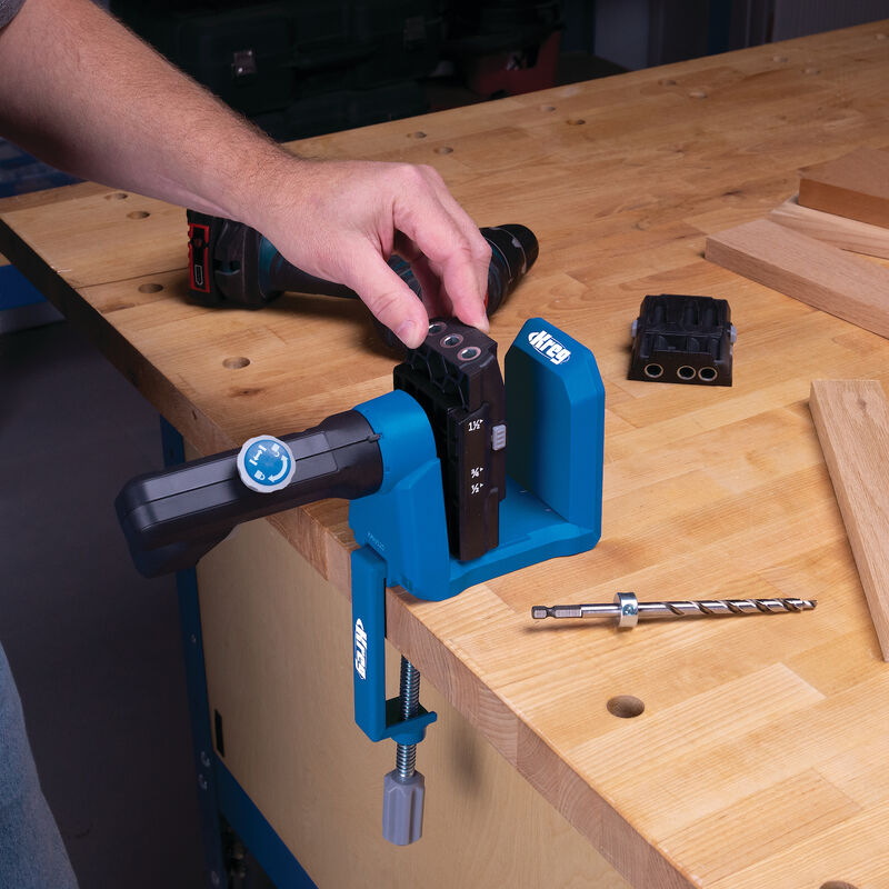 Pocket hole jig clamped to workbench with drill bit and woodworking tools visible
