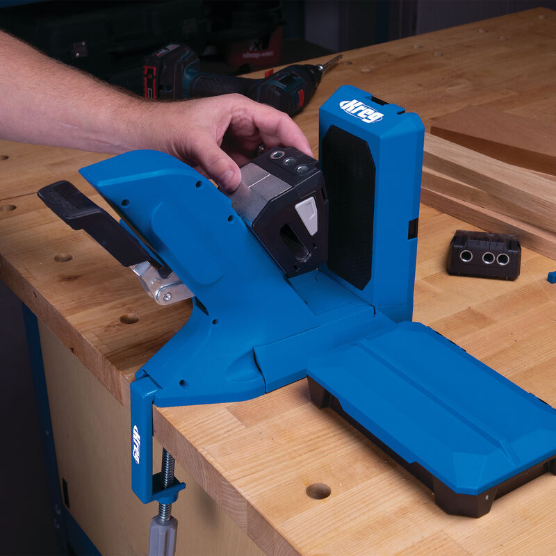 Person using blue pocket hole jig woodworking tool on workbench with wood pieces