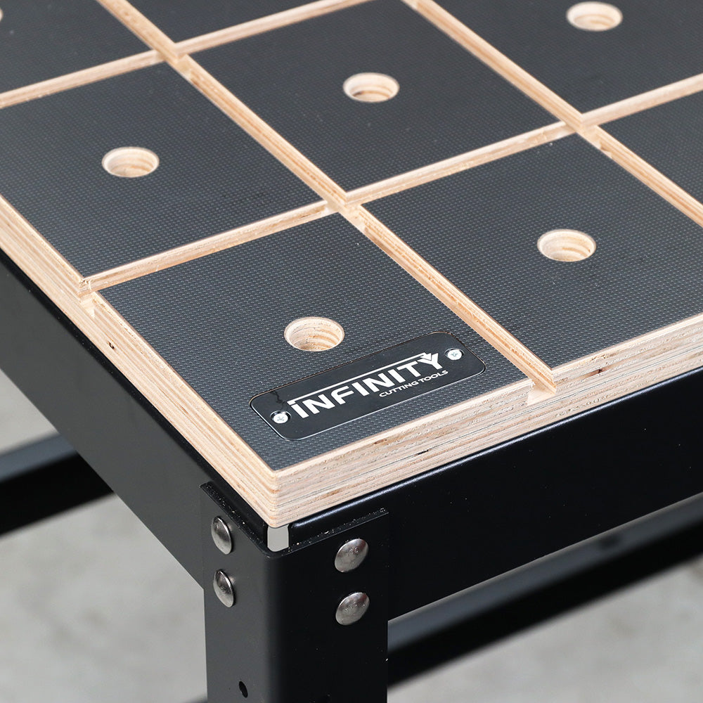Workbench corner with grid-patterned surface, dog holes, and visible Infinity label
