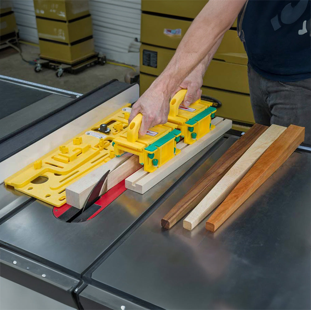 Woodworker using yellow push blocks to guide wood across a table saw for precise cutting.