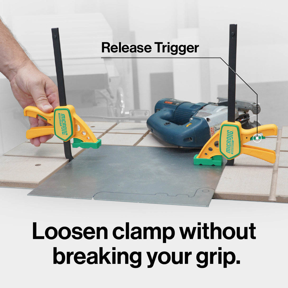 Quick-release woodworking clamps securing metal sheet on workbench with power tool nearby