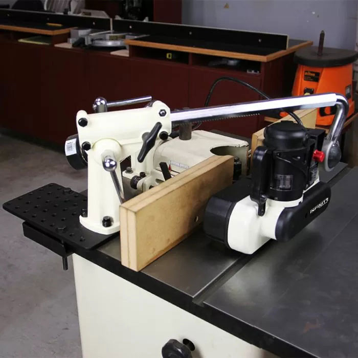 Woodworking power feeder mounted on a table saw with a fence in a workshop setting