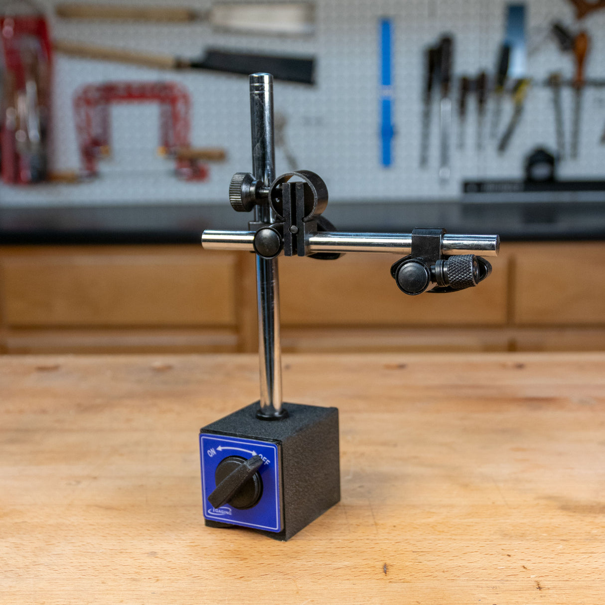 Magnetic base tool holder with adjustable arms on a woodworking bench
