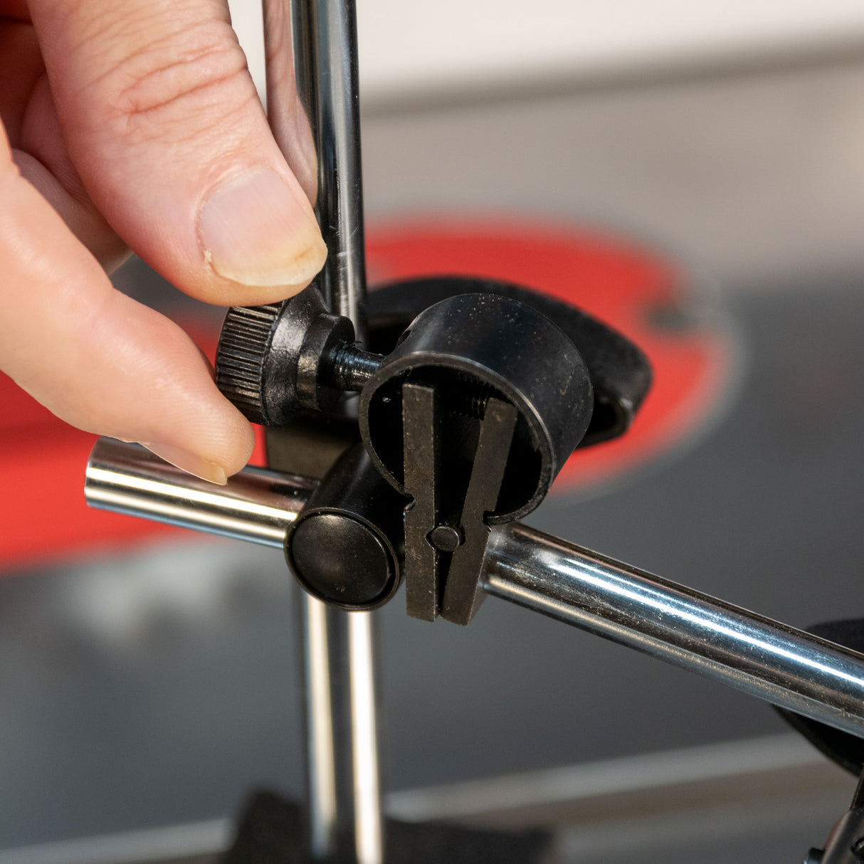 Close-up of hand adjusting magnetic base clamp on metal rods for woodworking tool setup