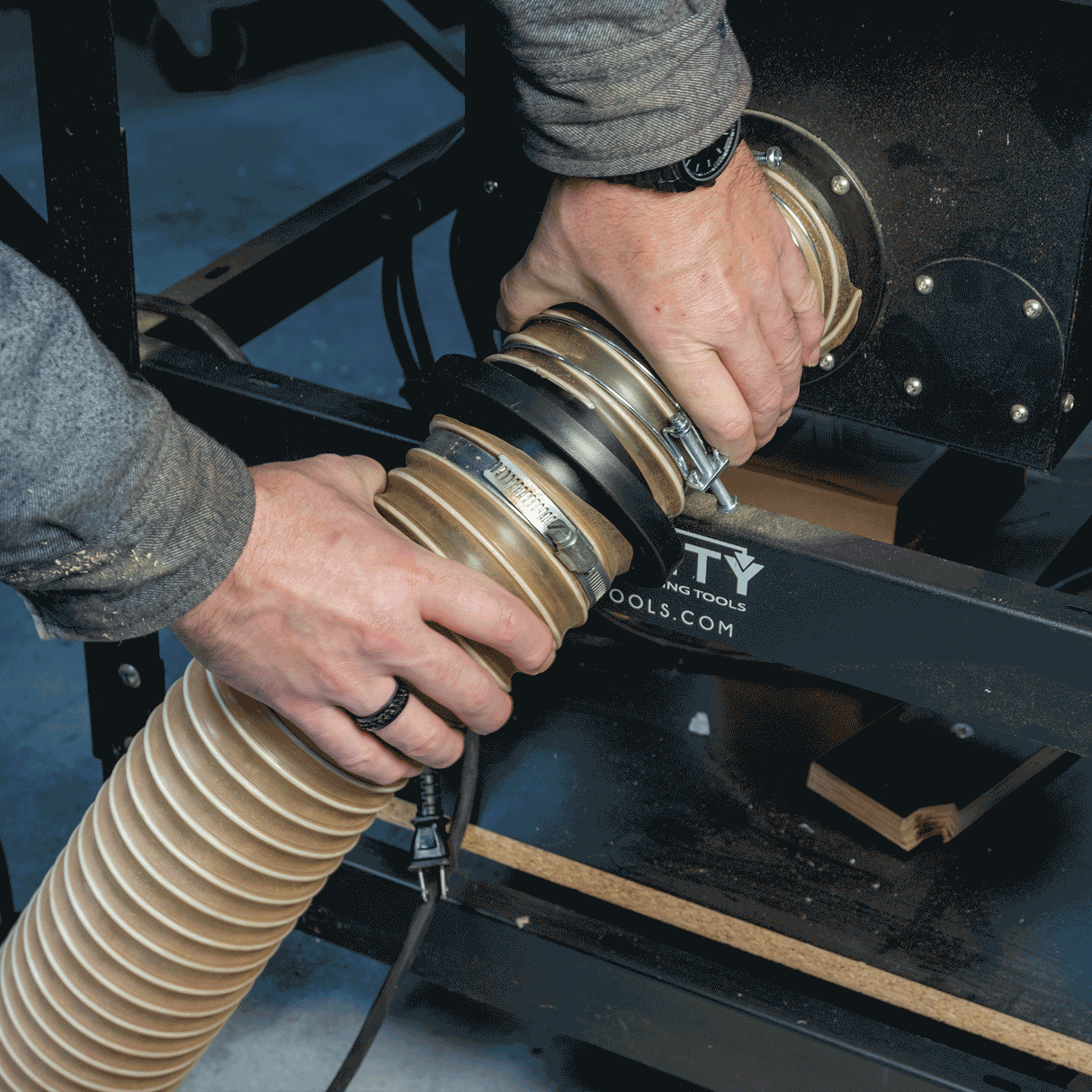 Hands connecting dust collection hose with magnetic coupling on woodworking machine