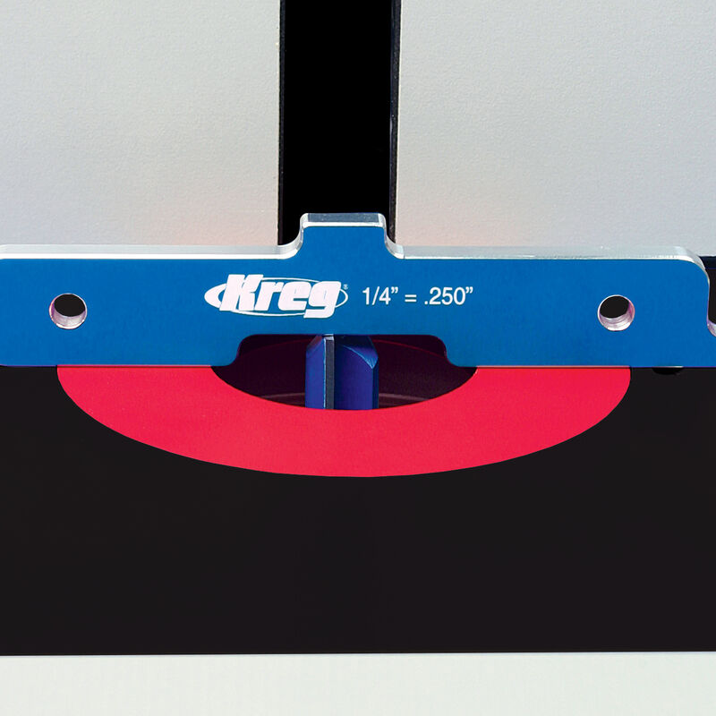 Router table setup with blue Kreg measuring guide, red insert plate, and router bit