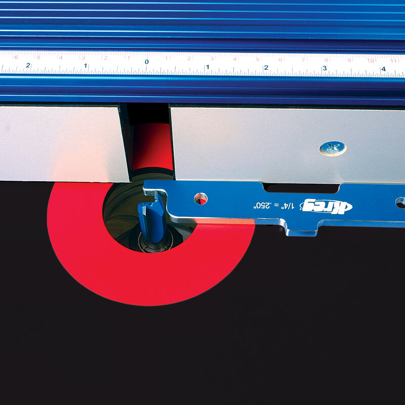 Router table setup with blue aluminum fence, scale, and red safety guard for precision woodworking.