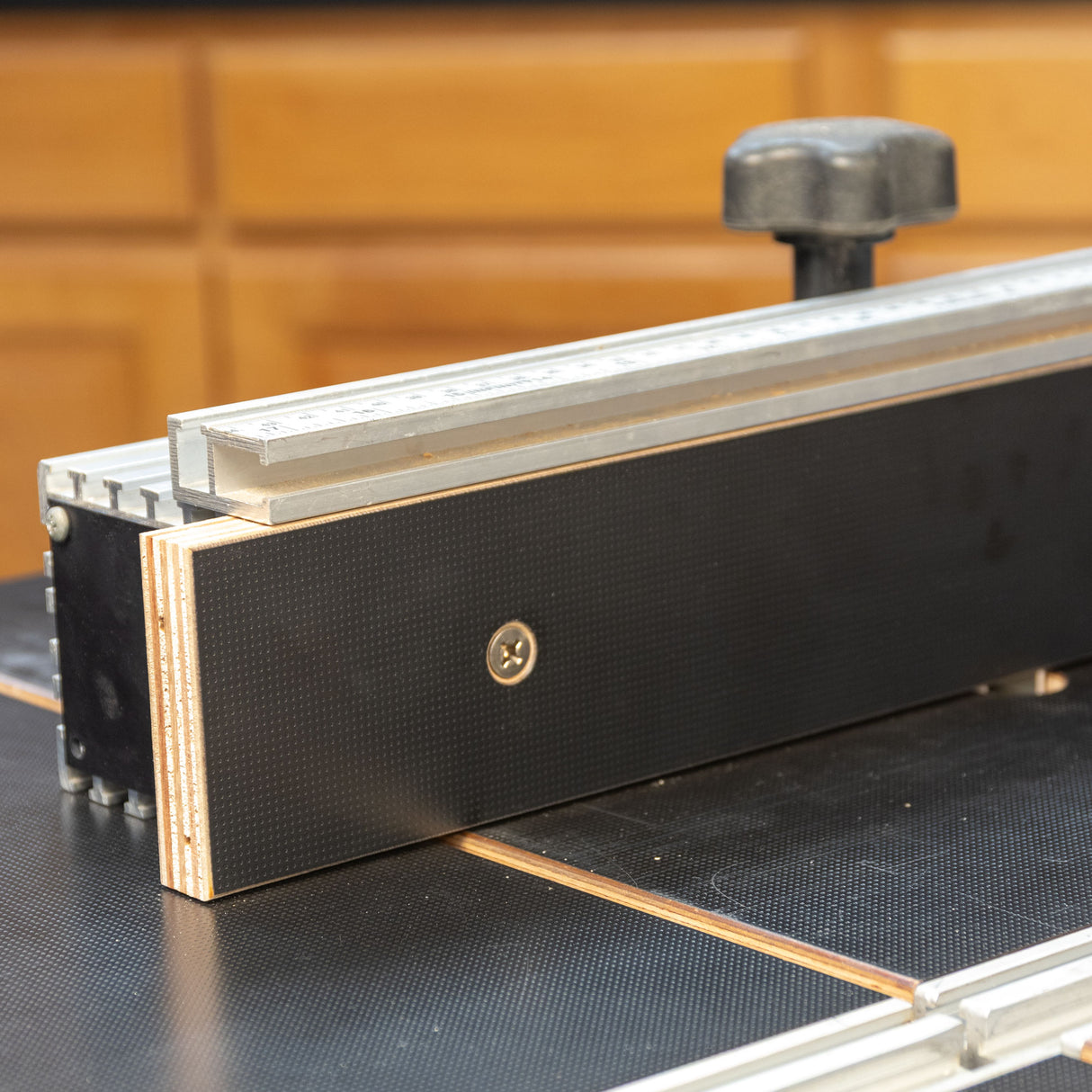 Router table fence with precision ruler and MDF face in a woodworking shop closeup