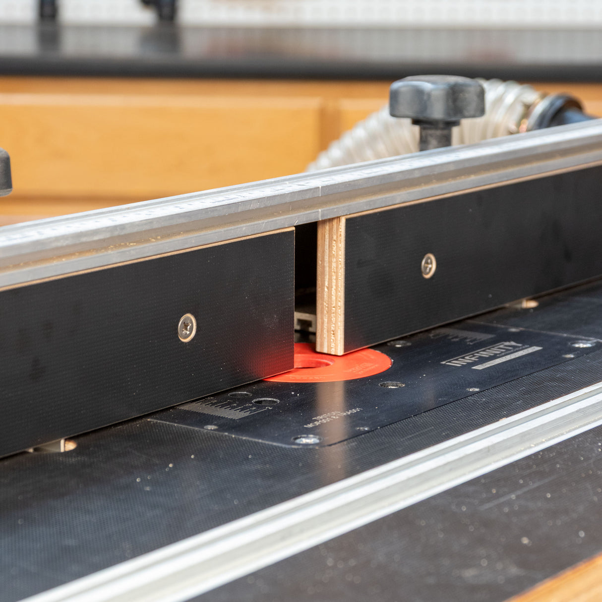 Router table closeup with MDF fence and dust collection in woodworking shop