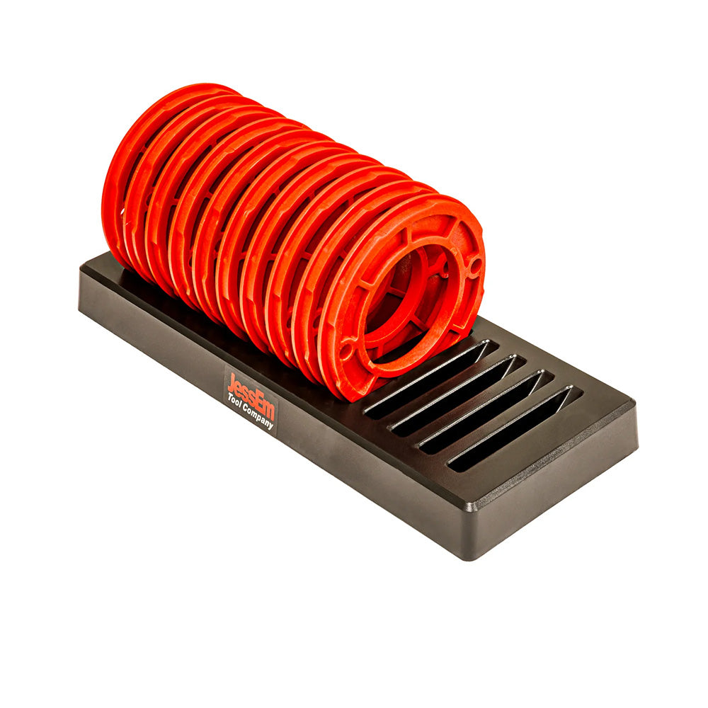 Set of red router table insert rings organized on a black holder for woodworking