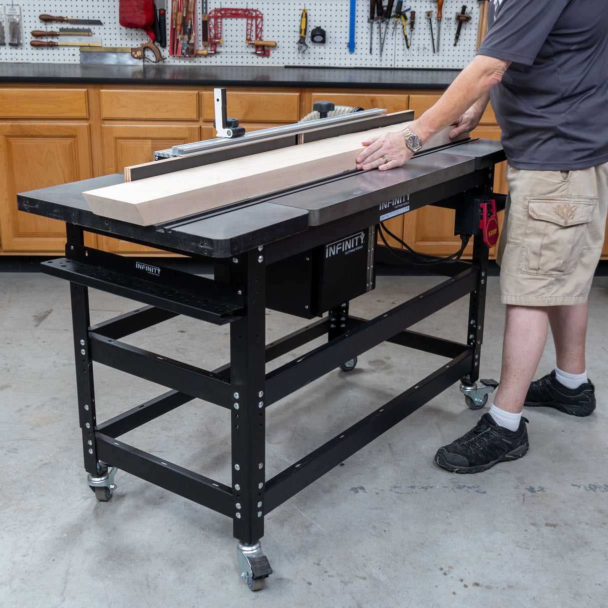 Woodworker feeding a long board across the Infinity Tools 1776 Freedom Class router table in a shop