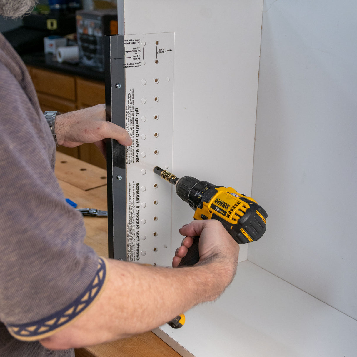 Using a shelf pin jig and drill to create evenly spaced holes in a cabinet