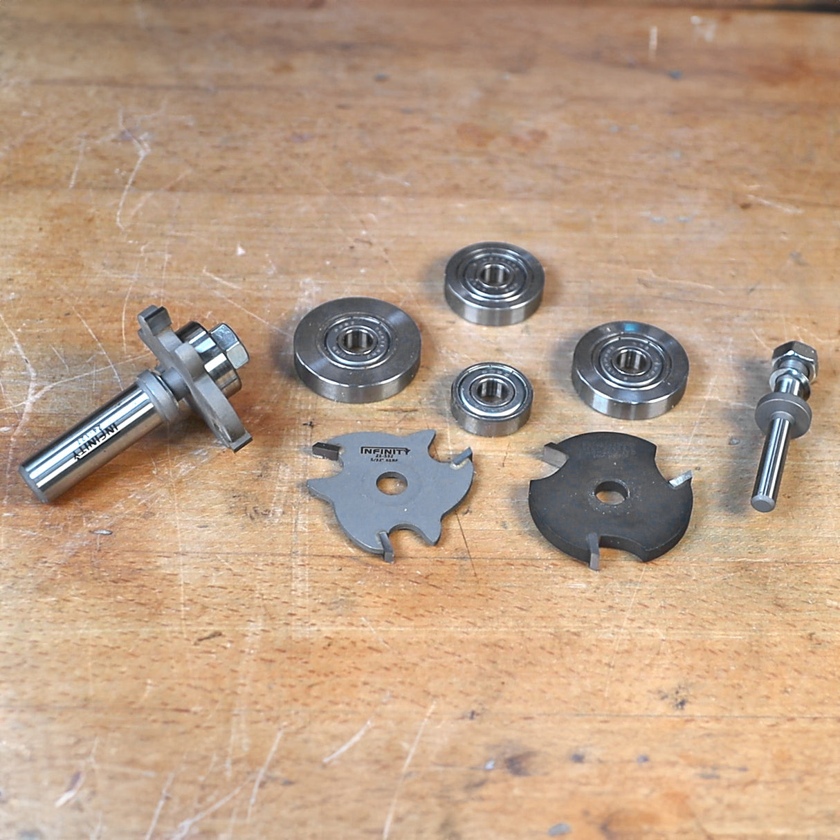 Woodworking router bit set with bearings and slot cutters on a workbench