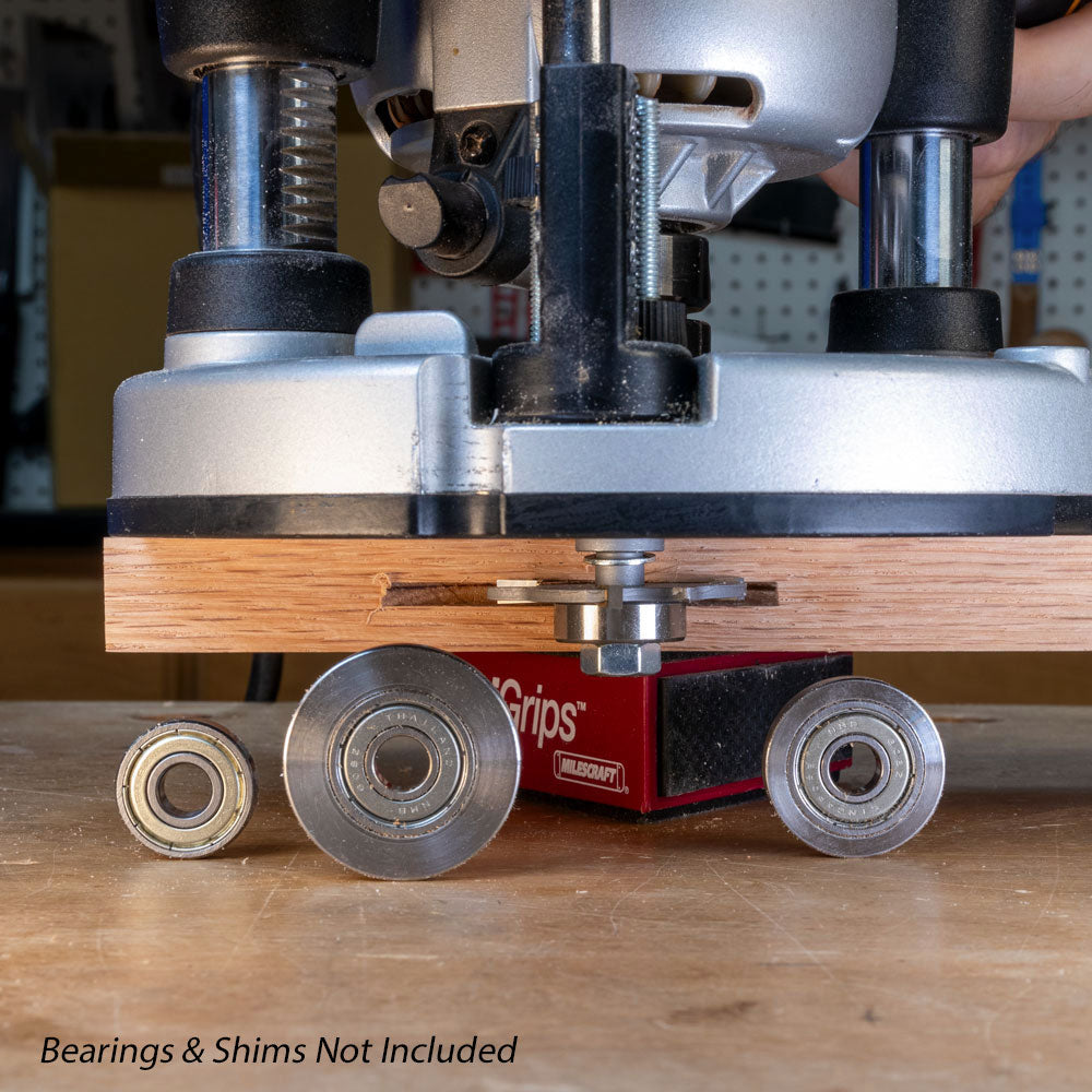 Slot cutter arbor installed in router cutting wood, with loose bearings and shims nearby.
