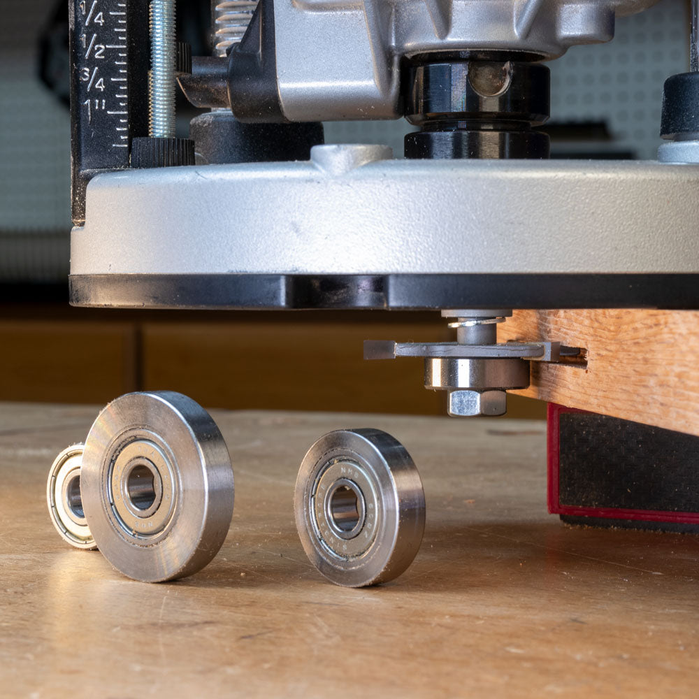Slot cutter arbor attached to router in use on wood, with bearings on a workbench