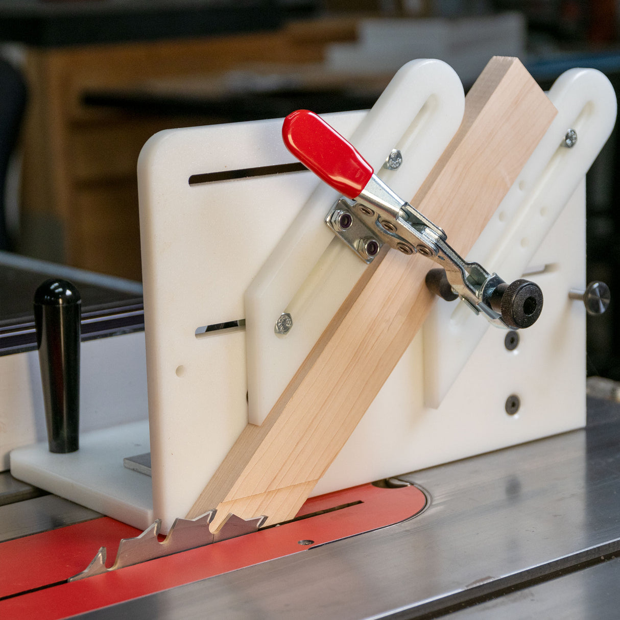 Table saw tenoning jig holding a wooden board with a red clamp for precise woodworking cuts