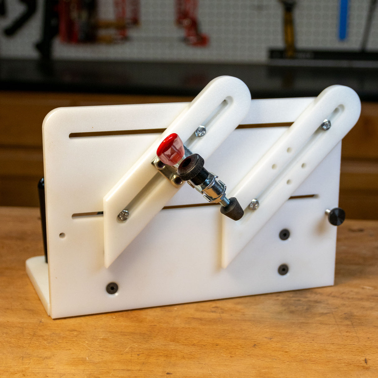 Adjustable vertical router sled jig on a woodworking bench, featuring slots and a clamp.