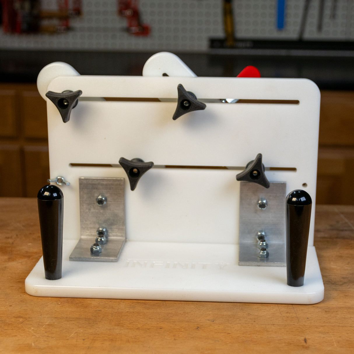 Vertical router sled with adjustable knobs and handles on a workbench in a workshop