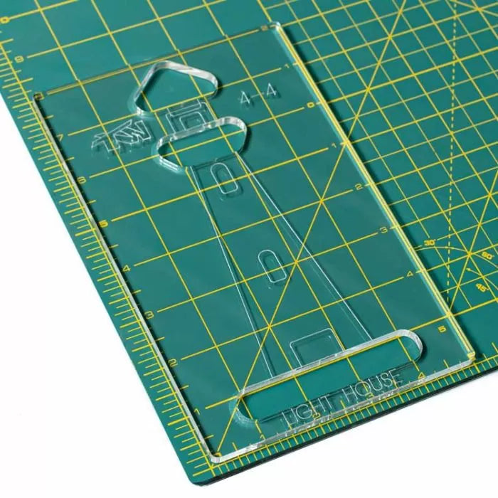 Acrylic quilting template with lighthouse cutout on a green cutting mat with yellow grid lines