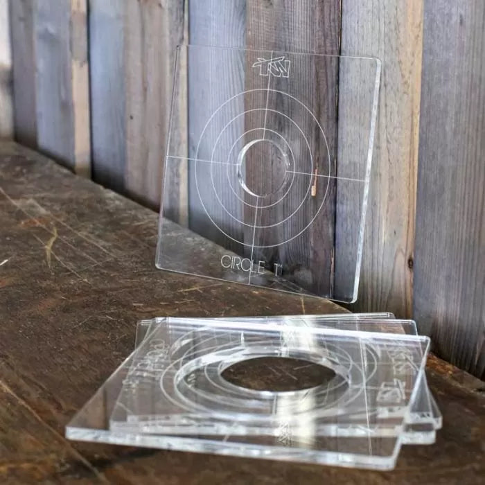 Clear acrylic router templates with circular guides on a rustic wooden surface for woodworking projects.