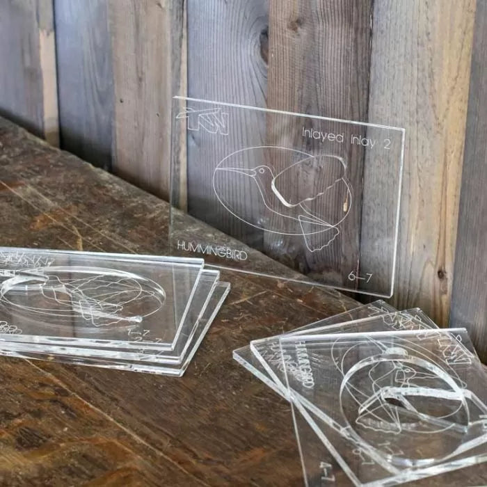 Stacked clear acrylic inlay templates with a hummingbird outline for woodworking projects