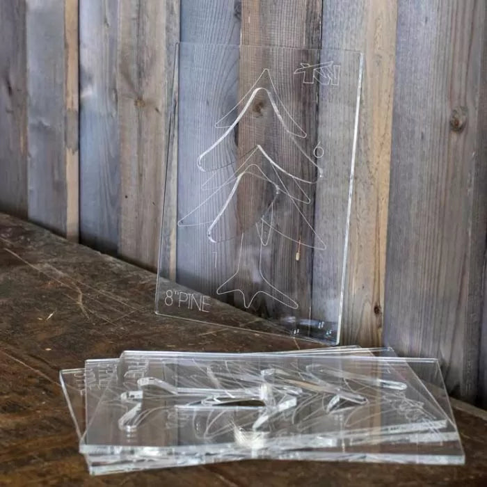 Acrylic woodworking templates with pine tree pattern on rustic wood surface
