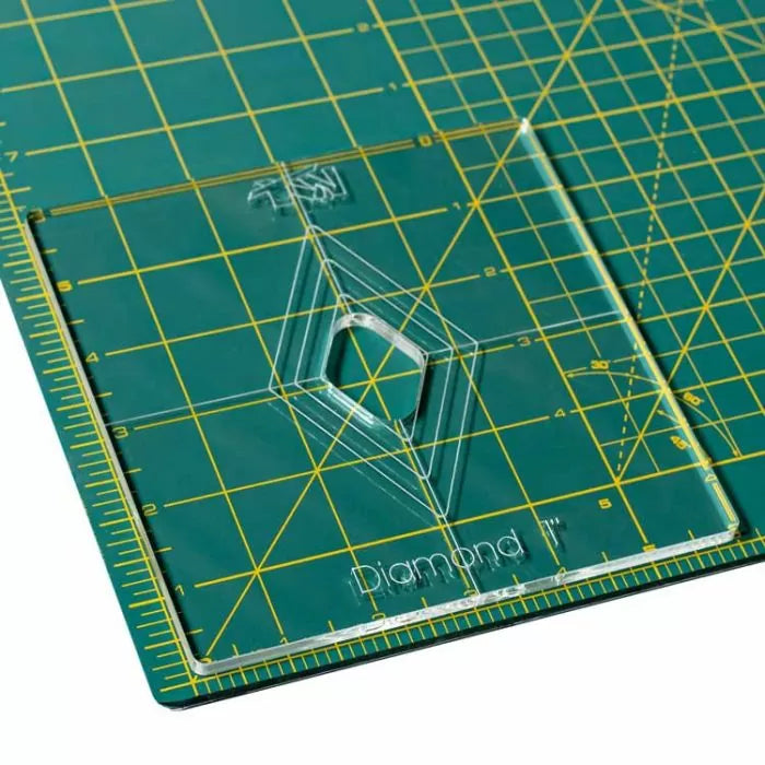 Acrylic diamond quilting template on a green cutting mat with yellow grid lines.