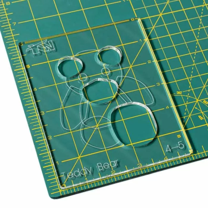 Clear acrylic teddy bear template on green self-healing cutting mat with measurement grid