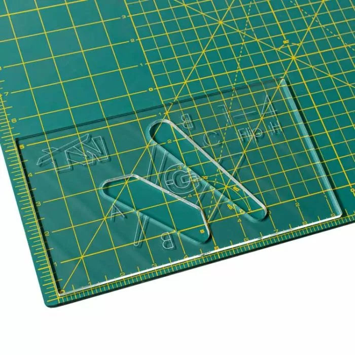 Acrylic woodworking template on green self-healing cutting mat with yellow grid lines.