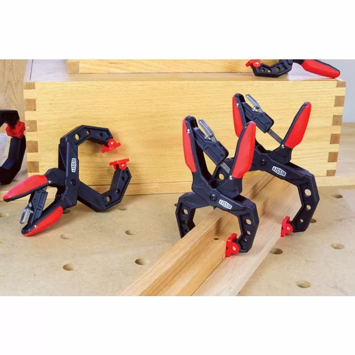 Corner clamps with red grips holding wooden boards for woodworking projects