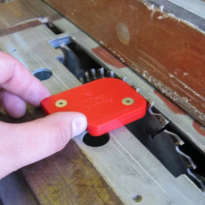 Hand using red table saw blade height gauge tool on woodworking saw blade