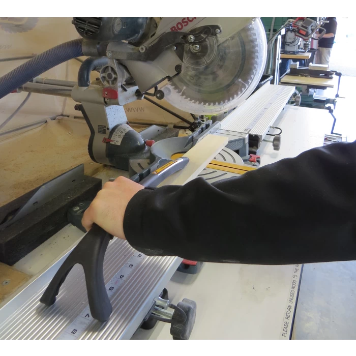 Person using a saw push stick to guide wood on a miter saw for safe woodworking cuts