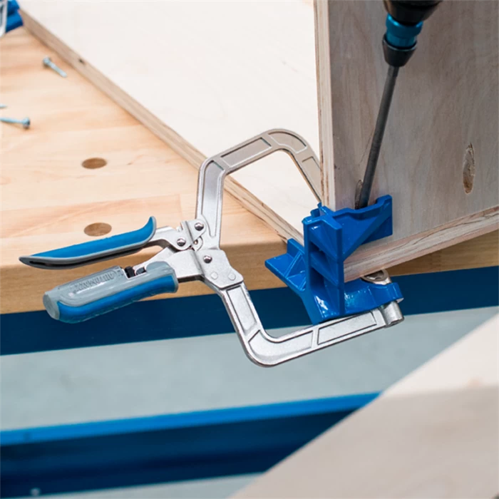 Pocket hole clamp securing plywood corner on workbench during woodworking assembly