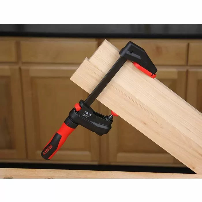 Woodworking clamp securing two wood boards on a workbench in a workshop setting