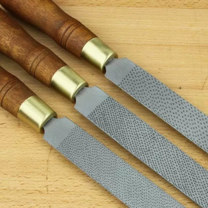 Set of woodworking rasps with wooden handles on a workbench, ideal for shaping wood.