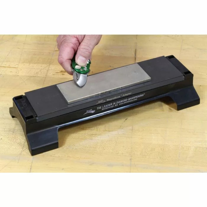 Sharpening a small pocket knife on a diamond sharpening stone on a wooden surface