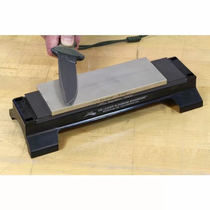 Hand sharpening a tactical knife on a diamond sharpening stone on a wooden surface