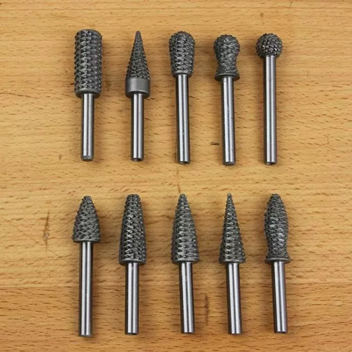Ten rotary burrs for woodworking or metal shaping on a wooden surface, various shapes and sizes